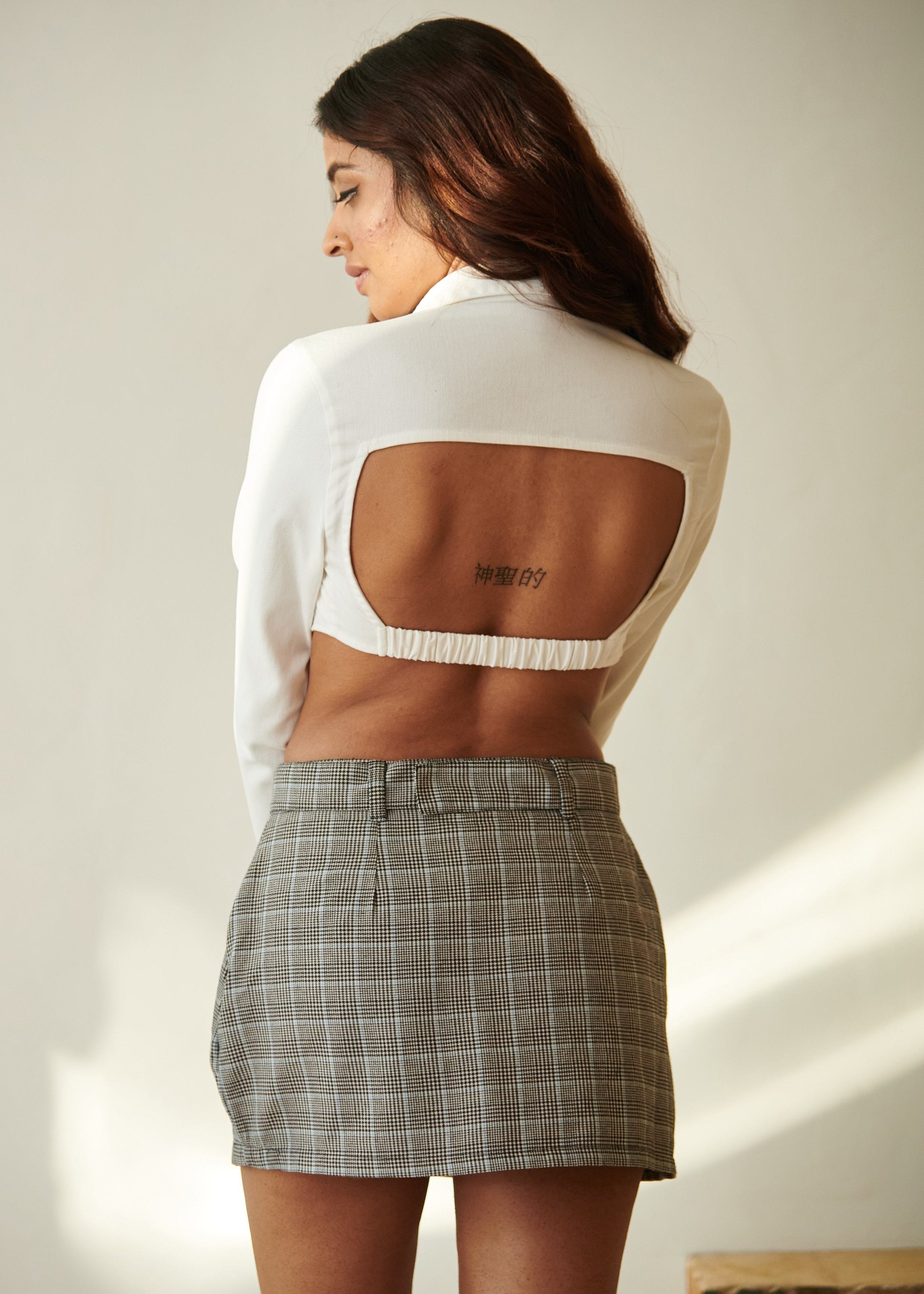 Stylish woman in an Almi White Crop Shirt and Plaid Skort Set, exuding modern and trendy vibes."