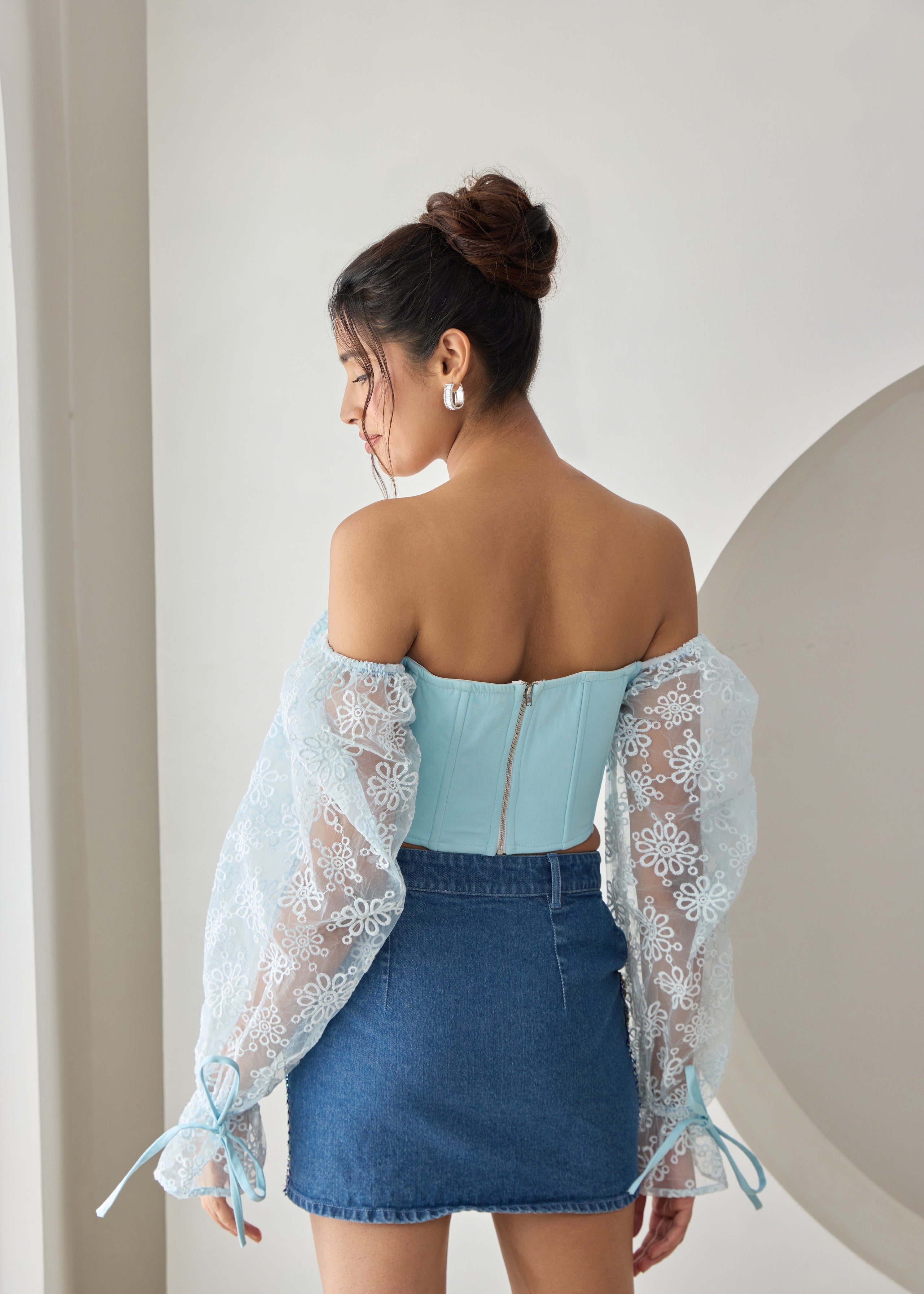 A baby blue corset top with embroidered details and organza sleeves.