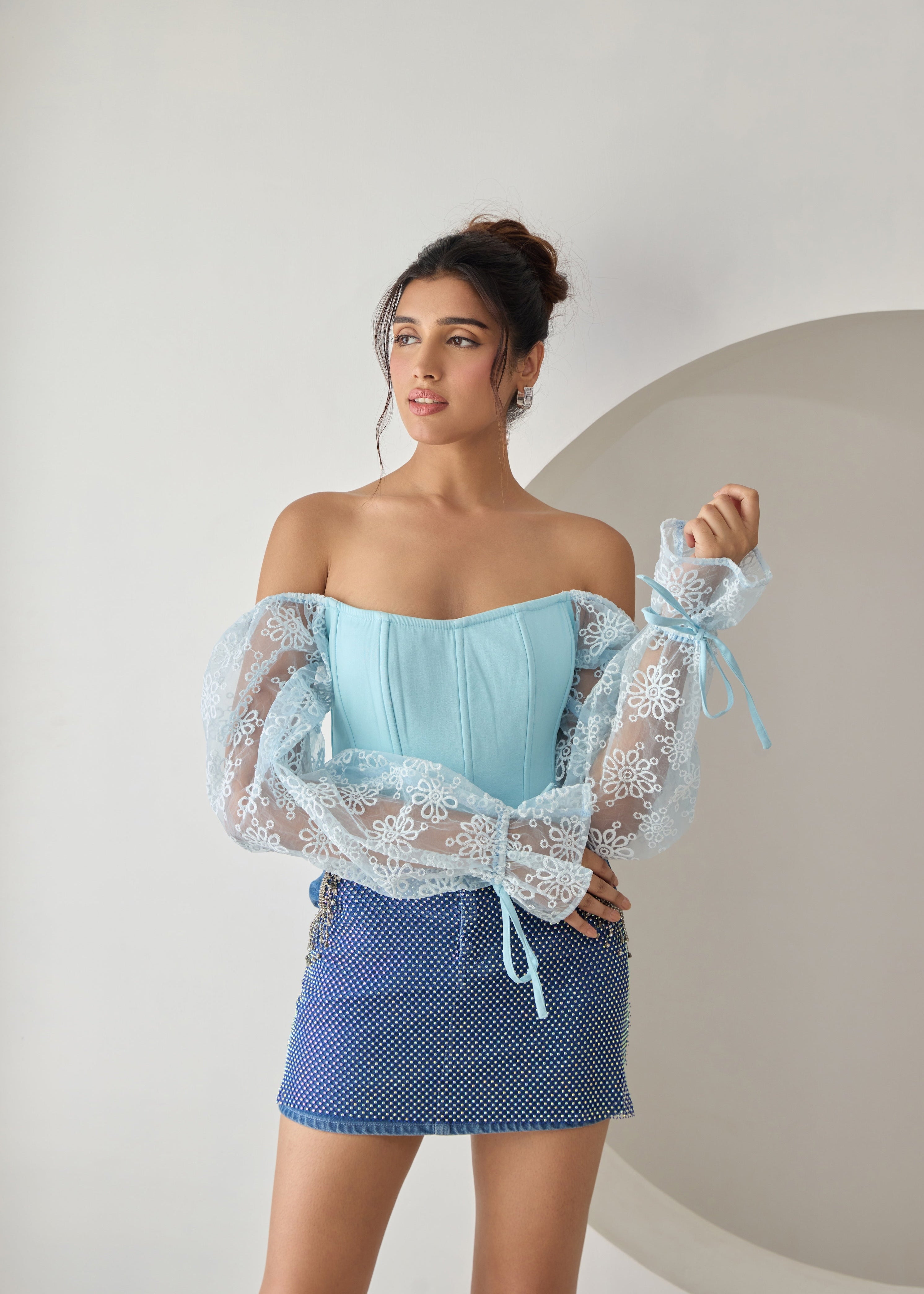 A baby blue corset top with embroidered details and organza sleeves.