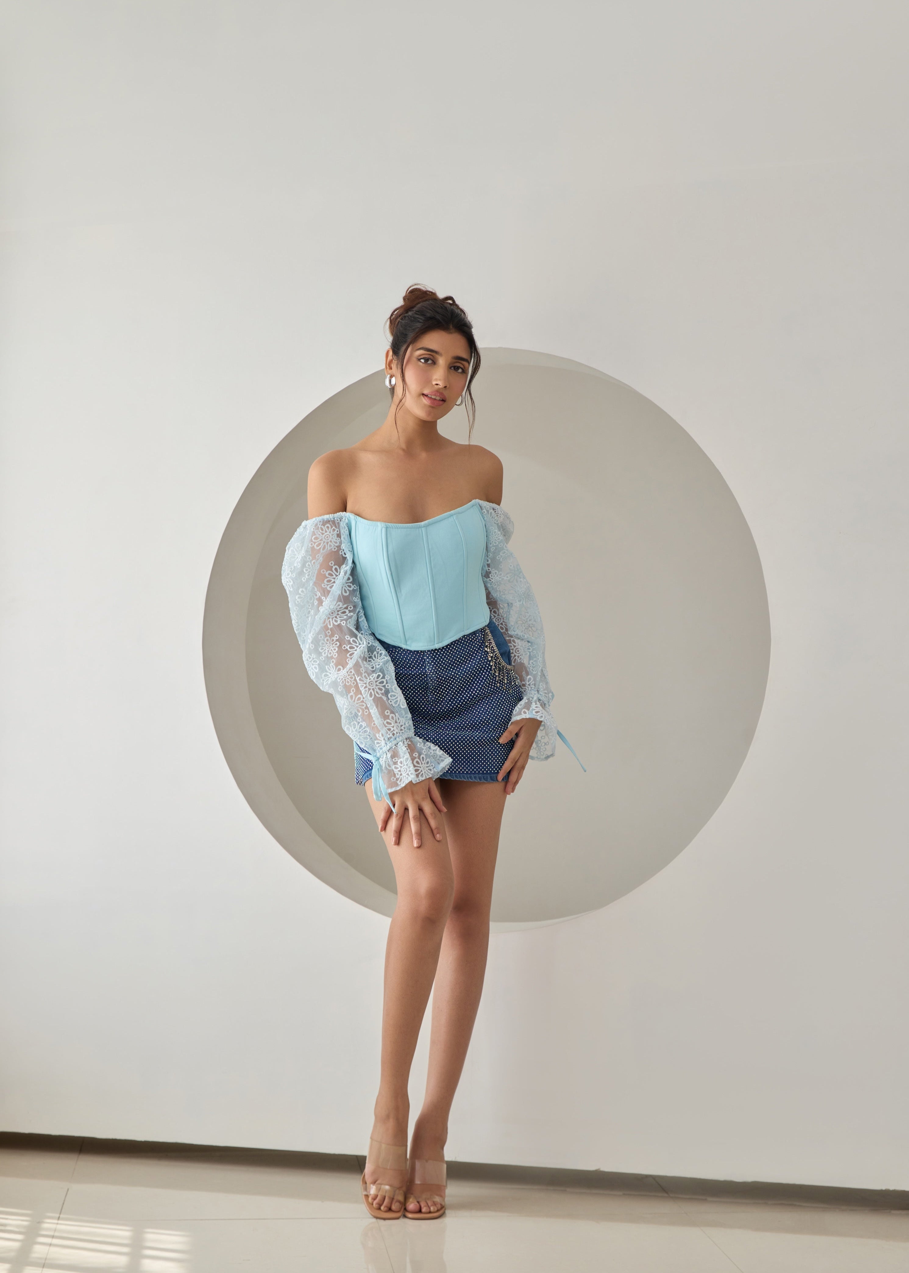 A baby blue corset top with embroidered details and organza sleeves.