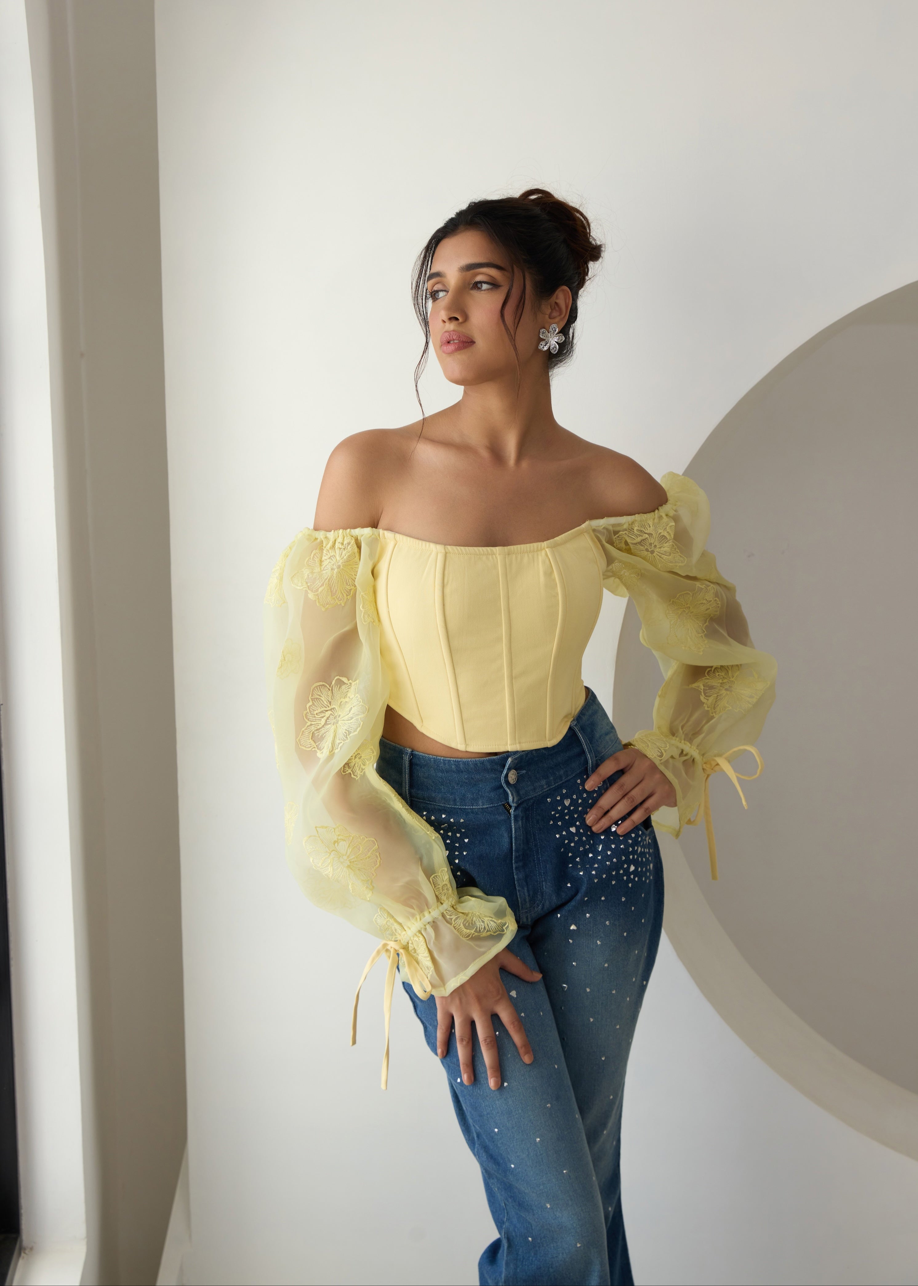 A yellow corset top with embroidered details and organza sleeves.