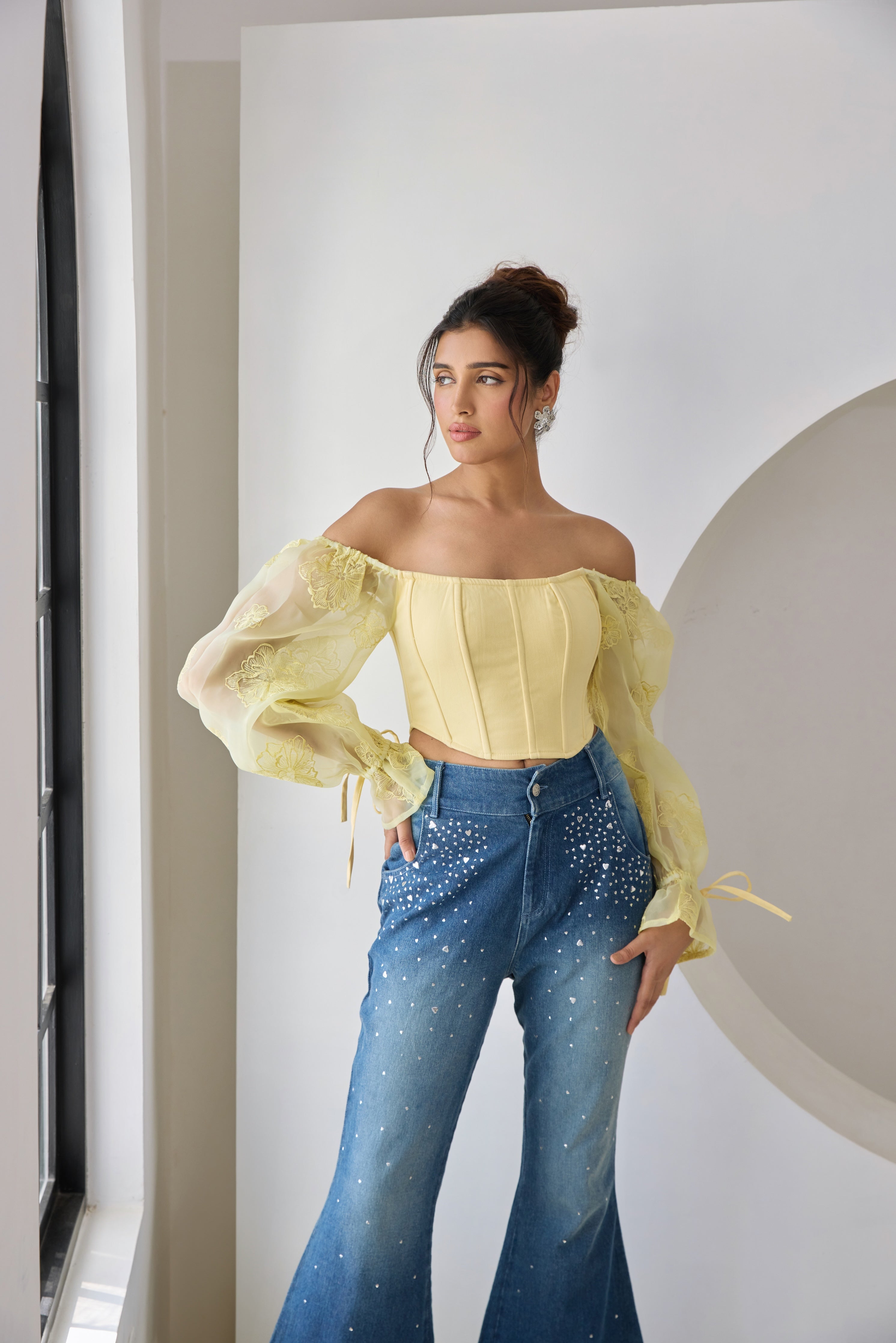 A yellow corset top with embroidered details and organza sleeves.