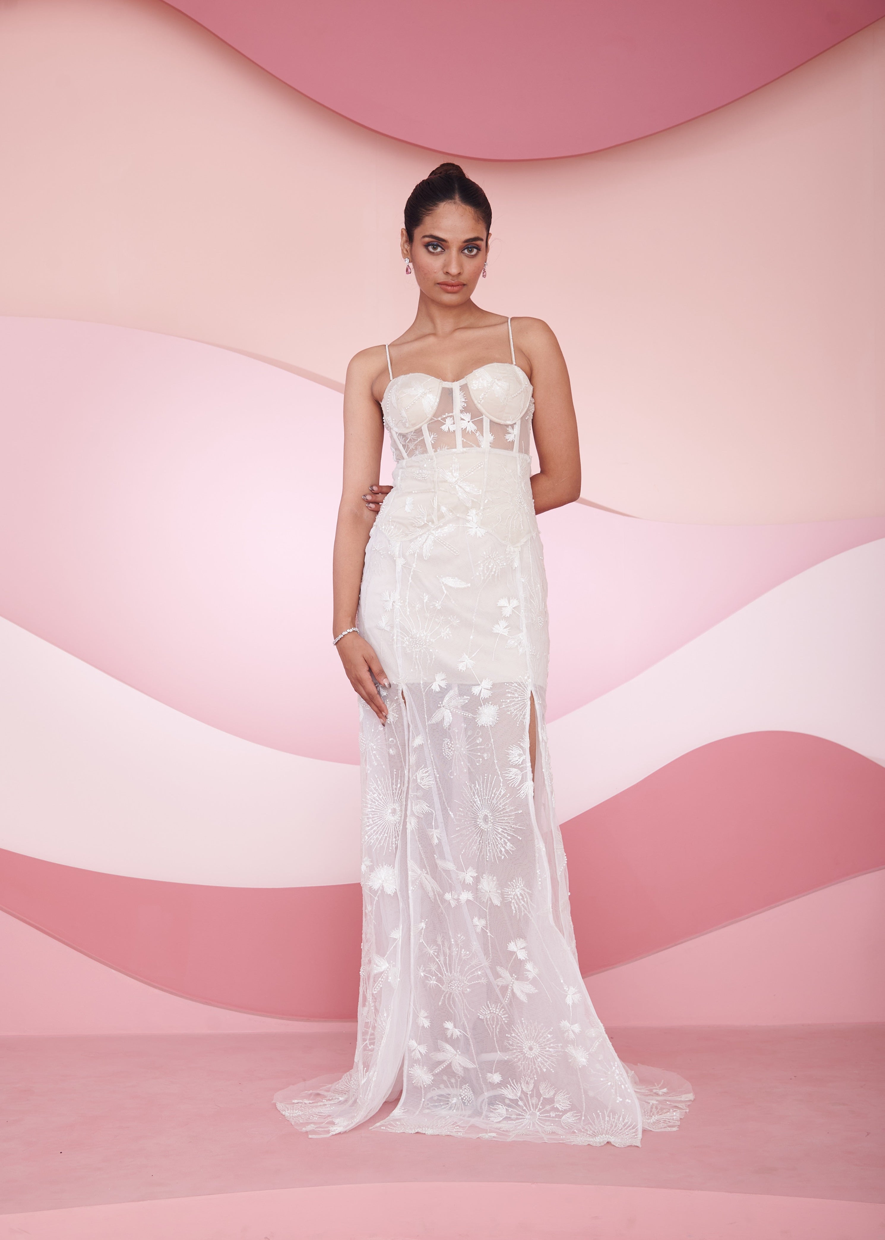 Nira white embroidered slit corset gown with intricate embroidery, a daring slit, and a fitted corset bodice, ideal for sophisticated occasions.
